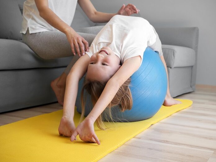 mother helping girl exercise ball mother helping girl exercise ball