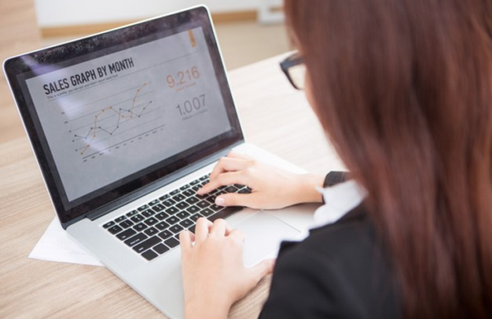 Woman working on her laptop screen having sales analytics open